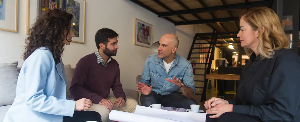 Grupo de vecinos reunidos en un salón revisando planos sobre la mesa