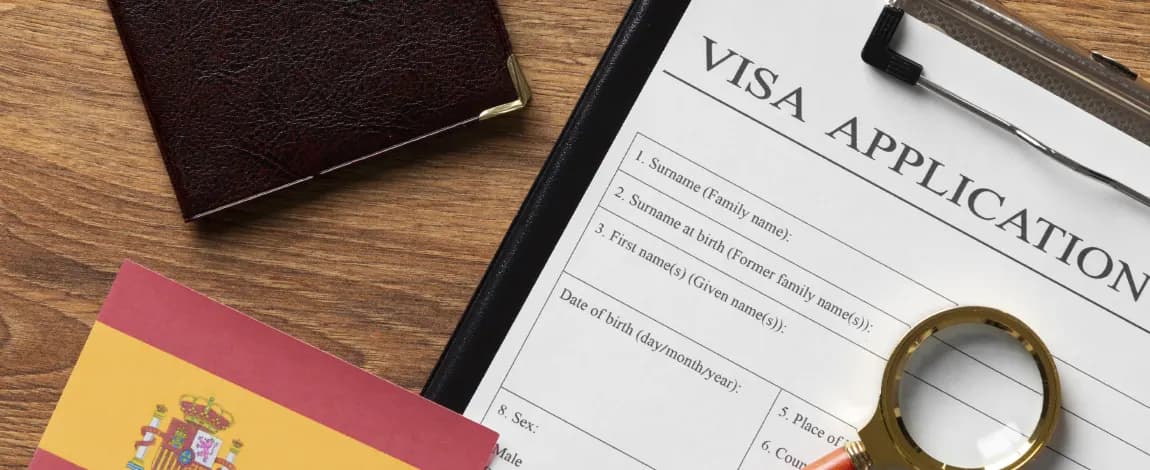 Formulario de solicitud de visado junto a un pasaporte español y una lupa sobre una mesa de madera