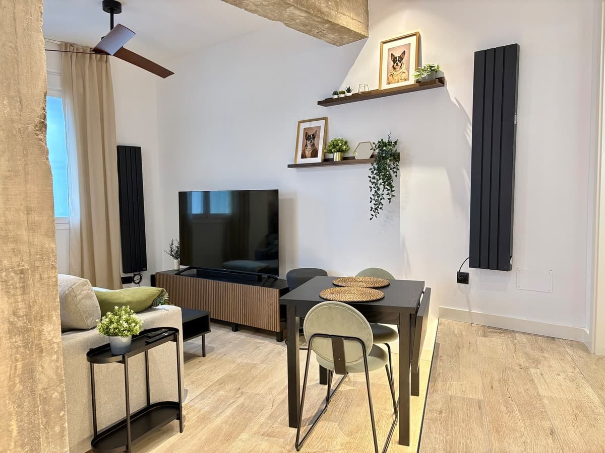 Salón de una vivienda gestionada, con mesa de comedor, baldas y suelo de madera