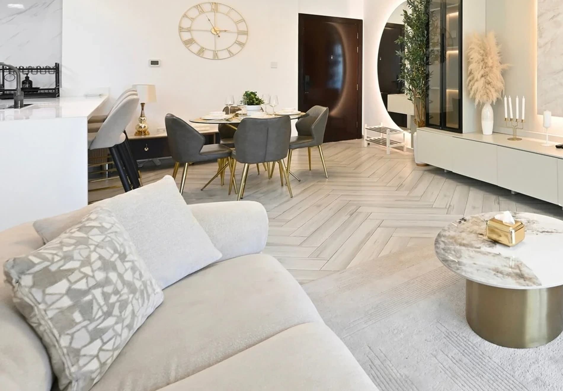 Living and dining room of a managed property, with herringbone floors, a light sofa and a marble coffee table