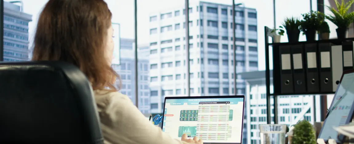 Mujer trabajando con un panel de indicadores financieros en su portátil en una oficina